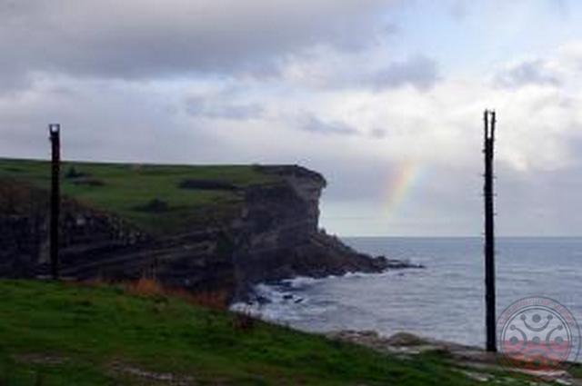 Panorámica del lado izquierdo de los acantilados con un arco iris en el mar Catábrico