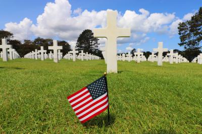 Bandera americana frente al camo de cruces blancas en el cementerio 